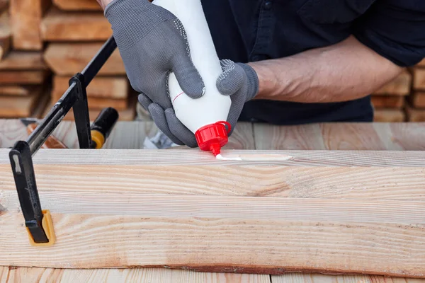 Manos de carpintero macho usando pegamento de madera y madera en una mesa de madera para muebles hechos a mano. De cerca. Hobby para el hombre . — Foto de Stock