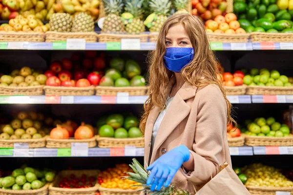 Coronavirus Covid-19 salgını sırasında alışveriş. Yüz maskeli ve eldivenli kadın marketten narenciye alır..