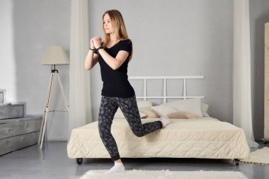 Evde kız eğitimi ve egzersiz. Sağlıklı bir yaşam tarzı için egzersiz dersleri alan formda bir kız. Kadın ev işleri için karantina kullanıyor.