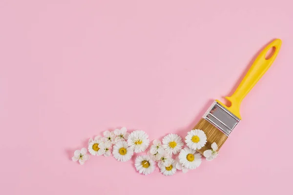Yaratıcı bahar çiçeği konsepti. Pembe pastel arka planda çiçekli boya fırçası. Bahar geldi. Metin için boşluk.
