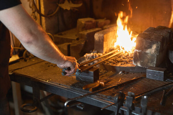 Blacksmith manually forging on iron on anvil at forge. Treatment of molten metal close-up.