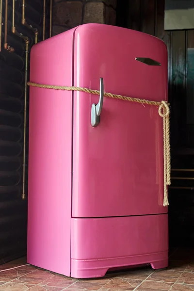 Closed pink refrigerator tied with a rope. A locked fridge as concept of food restrictions or diet.