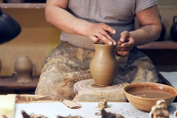 Potter au travail. Lieu de l'atelier. Les mains d'un potier créant un pot sur le cercle. — Photo