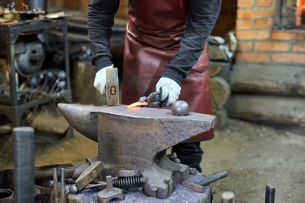 Blacksmith manually forging on iron on anvil at forge. Treatment of molten metal close-up. — Stock Photo, Image