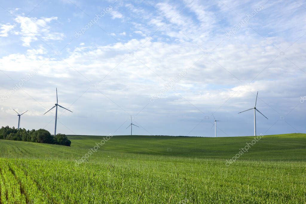 Wind turbine on the green grass over the blue clouded sky. Protection of nature. Wind turbine - renewable energy source.