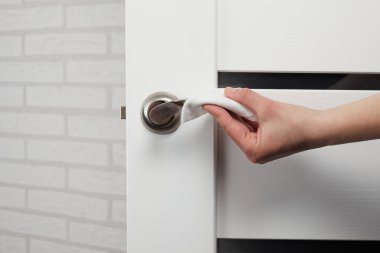 Kadın eli, kapı kollarını dezenfekte etmek için antibakteriyel ıslak mendil kullanıyor. Koronavirüs salgını sırasında korunma. Kapat..