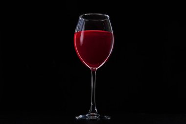Siyah arka planda bir bardak kırmızı şarap. Koyu masada şarap kadehi. Cabernet içeceği..