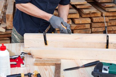 Erkek marangoz elleri, ahşap bir masada el yapımı mobilyalar için alet ya da ekipman kullanıyor. Kapat..