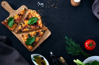 İtalyan pizzası ve pizza pişirme malzemeleri arka planda. Domates, zeytin yağı, otlar ve baharatlar..
