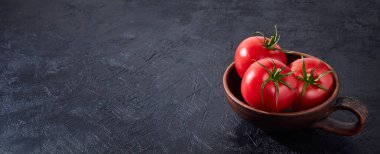 Kırmızı, koyu arkaplanda olgun domatesler. Taze domates topluyorum. Siyah masa.