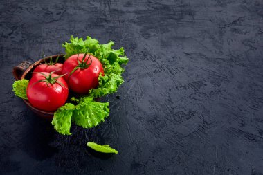 Salata salatalı taze üzüm domatesleri siyah taş arka planda yapraklar. Vejetaryen sebze diyeti. Bitki, domates, aşçılık konsepti.