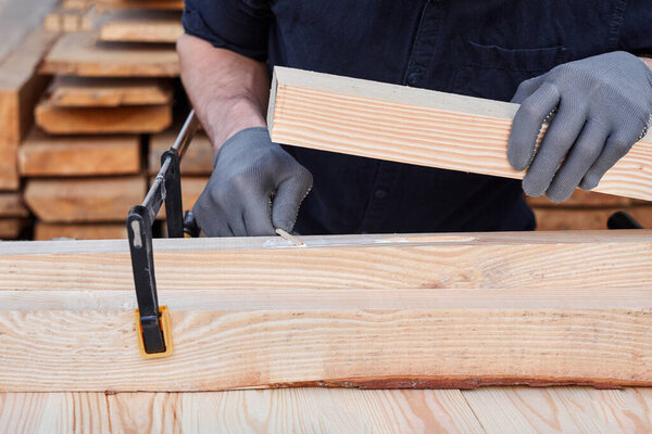 Male carpenter hands using wood glue and timber on a wooden table for handmade furniture. Close up. Hobby for man. Wooden table.