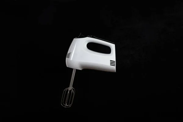 Modern mixer or hand mixer for kitchen cooking isolated on dark background. Electric tool with beaters for mixing food.