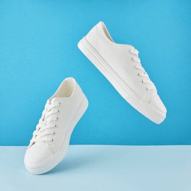 Bir çift şık beyaz spor ayakkabı, Pastel mavi arka planda koşu ayakkabısı..