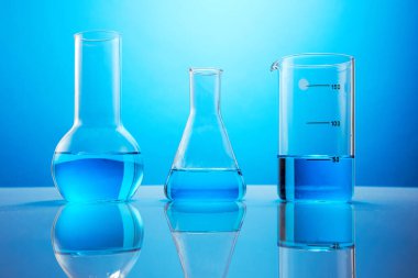 Mavi arka planda mavi bir sıvı bulunan laboratuvar bardakları. Kimyasal analiz. Deney tüpleri için test tüpleri.