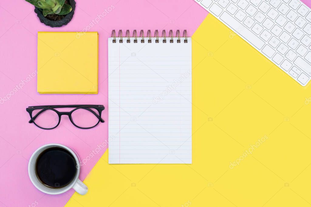 pink and yellow colorful working place layout. note book paper. diary, textbook, writing. coffee, keyboard and glasses. spring concept. copy space flat lay