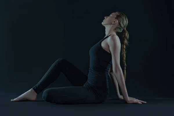 年轻女子练习瑜伽姿势 瑜伽垫和腿在黑暗的黑色背景上 复制空间 运动健美运动 — 图库照片