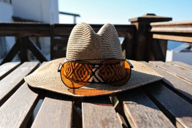 Tahta terasta güneş gözlüklü hasır şapka