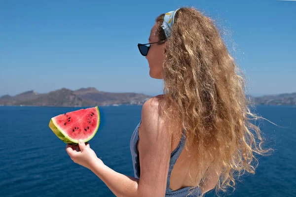 Bir dilim karpuzla güzel bir kadın deniz manzaralı mayo giyiyor yaz tatili için.