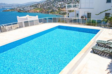 Otelde ya da güneşli bir günde tatil köyünde turkuaz renkli su ile yüzme havuzu.