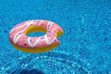 Yüzme havuzunda yüzen pembe şişirilebilir donut donutu. Plaj havuzu aksesuarları. Yaz tatili kavramı
