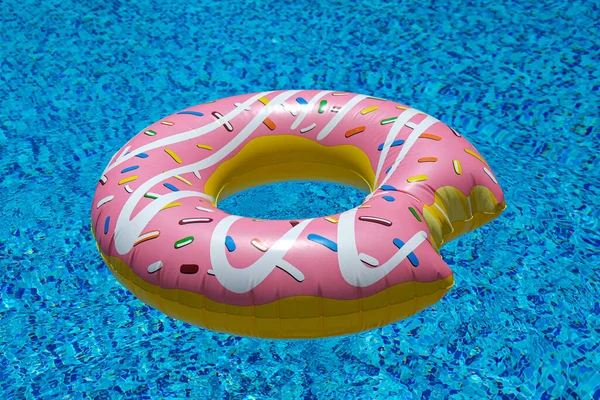 Yüzme havuzunda yüzen pembe şişirilebilir donut donutu. Plaj havuzu aksesuarları. Yaz tatili kavramı