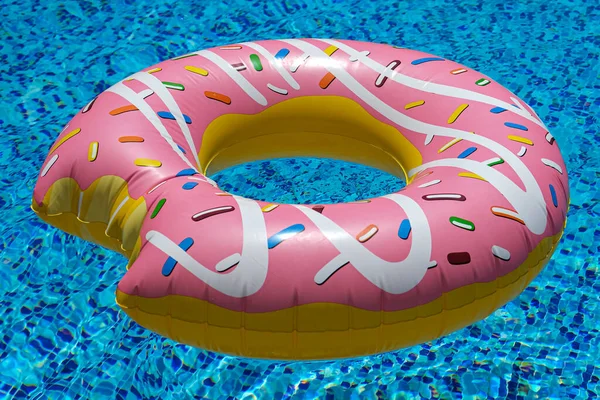 Yüzme havuzunda yüzen pembe şişirilebilir donut donutu. Plaj havuzu aksesuarları. Yaz tatili kavramı.
