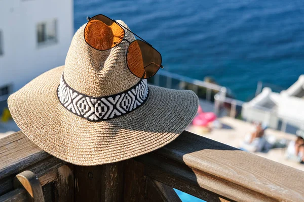 Güneş gözlüklü hasır şapka. Tatil köşkünün ahşap terasında. Ya da deniz manzaralı otel.