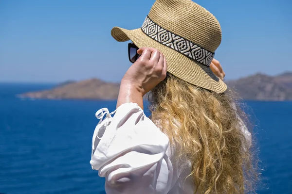 Hermosa mujer joven en gafas de sol vestido blanco y sombrero de paja bikini mirando a la vista al mar en la villa del hotel resort —  Fotos de Stock