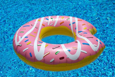 Yüzme havuzunda yüzen pembe şişirilebilir donut donutu. Plaj havuzu aksesuarları. Yaz tatili kavramı.