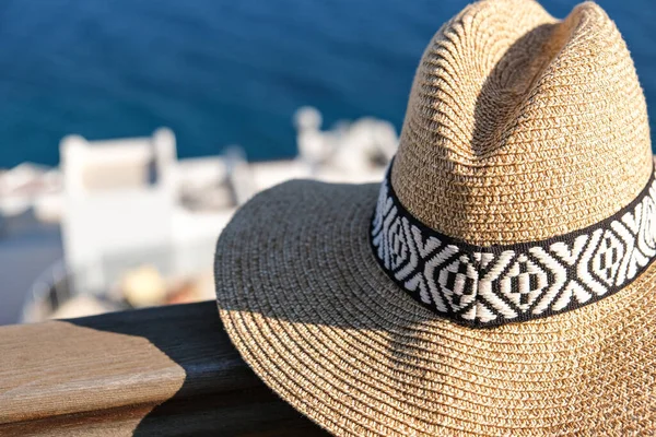 .straw hat on wooden terrace of holiday villa or hotel with sea and wimming pool view.