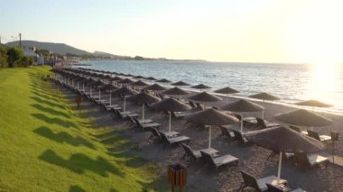 Gün batımında deniz kıyısında güneş yatakları ve şemsiyeler..             