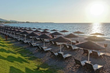 Gün batımında deniz kıyısında güneş yatakları ve şemsiyeler..                              