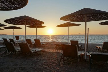 Gün batımında deniz kıyısında güneş yatakları ve şemsiyeler..             