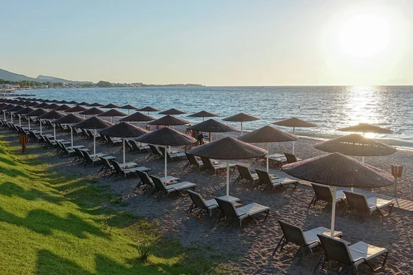 Gün batımında deniz kıyısında güneş yatakları ve şemsiyeler..                              