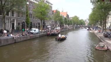 Amsterdam Kanalı 'nda tekneler, set boyunca yürüyen insanlar. Amsterdam, Hollanda, Temmuz 2019.