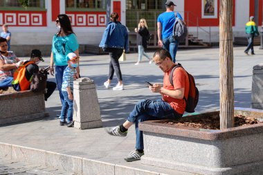 Moskova 'da bir sokakta oturan bir adam telefona bakar. Rusya Moskova Haziran 2020.