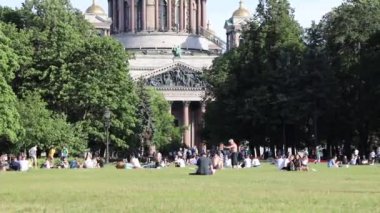 İnsanlar parkta çimlerde dinleniyor, St. Isasakievsky Katedrali manzarası, yaz günü. Rusya, Saint Petersburg Temmuz 2020