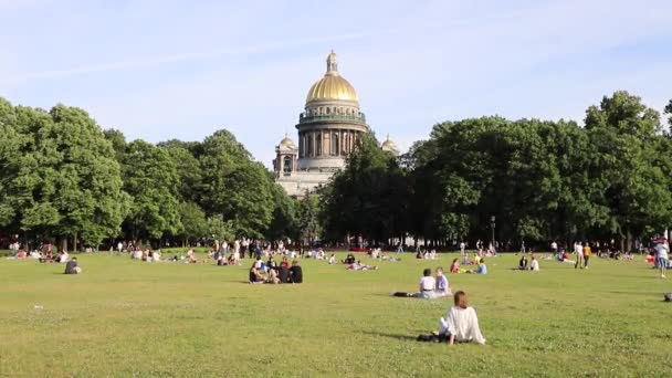 人々は公園の芝生の上で休み 聖Isasakievsky大聖堂 夏の日の景色 ロシア サンクトペテルブルク2020年7月 — ストック動画