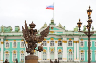 Alexander Sütunu 'nun çitinde, yaz günü Kış Sarayı' nın arka planına karşı çift başlı kartal. Rusya, Saint Petersburg Temmuz 2020