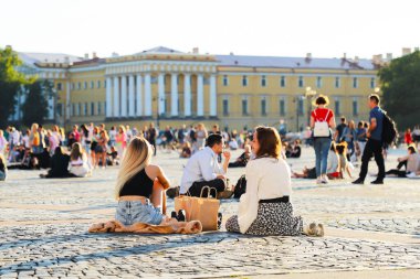 İnsanlar Saint Petersburg, Palace Meydanı 'ndaki kaldırım taşlarının üzerinde oturur ve rahatlarlar. Rusya, Saint Petersburg Temmuz 2020
