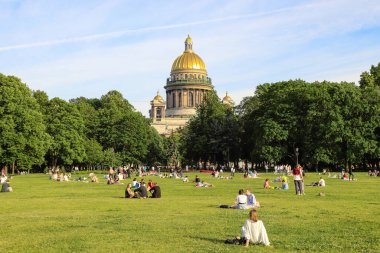 İnsanlar parkta çimlerde dinleniyor, St. Isasakievsky Katedrali manzarası, yaz günü. Rusya, Saint Petersburg Temmuz 2020