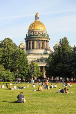 İnsanlar parkta çimlerde dinleniyor, St. Isasakievsky Katedrali manzarası, yaz günü. Rusya, Saint Petersburg Temmuz 2020