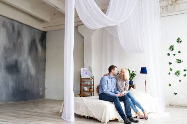 Yatakta oturmuş, Öpüşme ve sarılma sevgi dolu genç çift. Kavram aşk hikayesi