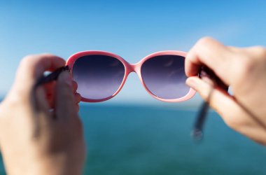 Güneş gözlüğü deniz üzerinde tutan el yumuşak odak. Tatil kavramı.