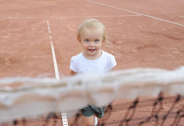 Tenis net arkasında küçük kız oynak portre portre. Şu tatlı bebeğe tenisçi portresi. Önden görünüm.