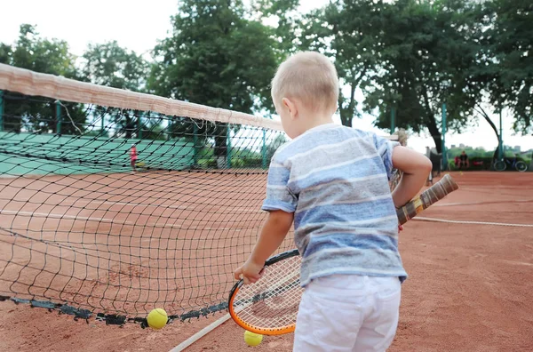 Küçük çocuk pratik tenis. Arkadan görünüm