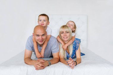 Evde yatakta yatarken iki küçük çocuklu mutlu aile. Mutluluk atmosferi onların etrafında olduğunu.