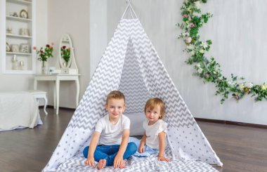 Teepee içinde kreş oturma sevimli mutlu küçük çocuklar. Yatay dikey