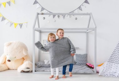 Güzel küçük çocuklar büyük gri süveterli çocuk odasında oynamak. Yatay dikey 